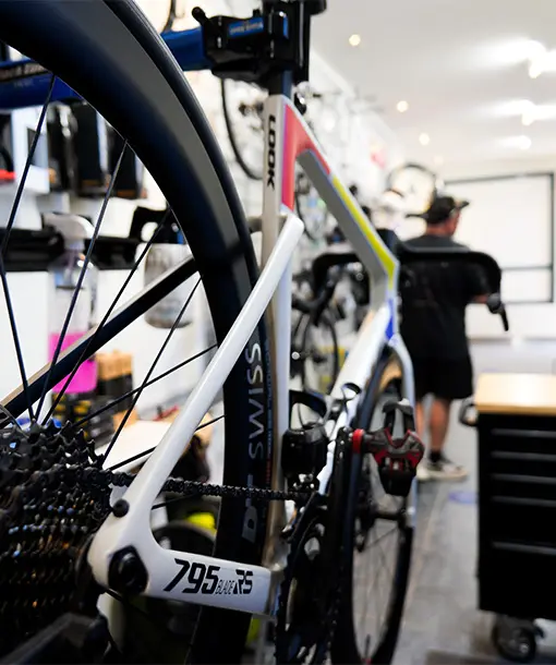 A LOOK 795 road bike in the foreground of a bike service workshop with a mechanic working in the background.